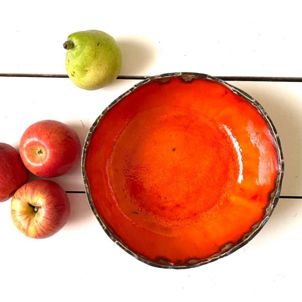 orange ceramic handmade bowl with dark glaze edge detail, fruit next to bowl