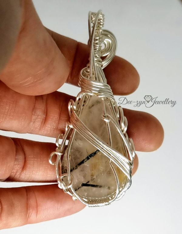 Rutilated Quartz and Rainbow Moonstone Captured in a Silver Filled Wire Sculptured Pendant. View of back of pendant, being held for sizing
