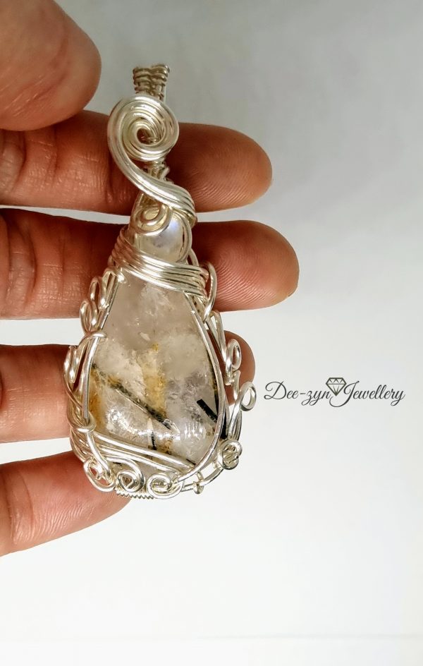 Rutilated Quartz and Rainbow Moonstone Captured in a Silver Filled Wire Sculptured Pendant on white background being held for sizing