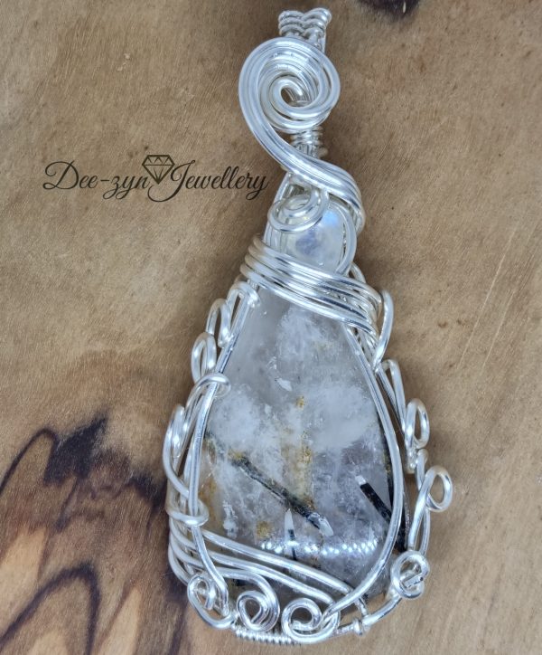 Rutilated Quartz and Rainbow Moonstone Captured in a Silver Filled Wire Sculptured Pendant on wooden background. view of front Really close up