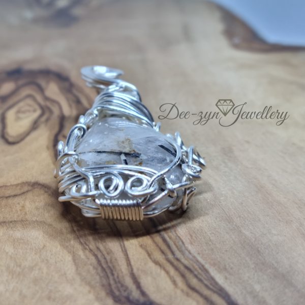 Rutilated Quartz and Rainbow Moonstone Captured in a Silver Filled Wire Sculptured Pendant on wooden background view of bottom of pendant