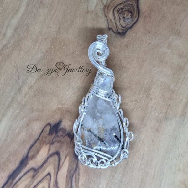 Rutilated Quartz and Rainbow Moonstone Captured in a Silver Filled Wire Sculptured Pendant on wooden background. view of front